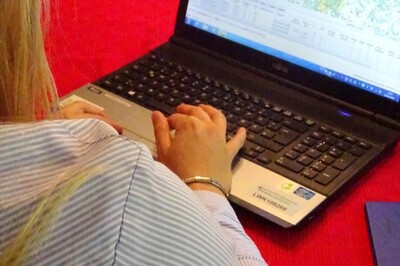 Person am Laptop mit Karte auf dem Bildschirm, sitzt an einem roten Tisch.