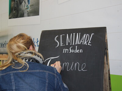 Bei ihrem Kreativworkshop zeigt Christine Gehle den Teilnehmer*innen Beispiele für originelle Tafelbeschriftungen.