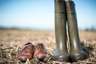 Schuhe und Stiefel im Stoppelfeld - © Wolfgang Ehrecke Ein Paar grüne Gummistiefel steht neben braunen Lederschuhen auf einem Stoppelfeld.