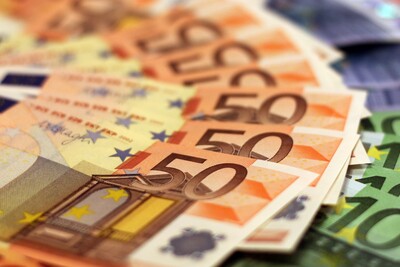 Verschiedene Euro-Banknoten in unterschiedlichen Werten liegen gestapelt und verteilt auf einer Fl&auml;che.