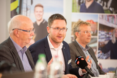 Markt-Fachmann Mathias Klahsen (M.), Kammerpräsident Gerhard Schwetje (l.) und Ökolandbau-Experte Markus Mücke während der Ernte-Pressekonferenz der Landwirtschaftskammer Niedersachsen am 18.09.2025 in Hannover-Ahlem. - © Christopher Hanraets Drei Männer in Anzügen sitzen an einem Tisch mit Mikrofonen und sprechen. Im Hintergrund sind unscharfe Fotos zu sehen.