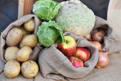 Werbung für Service vom Hof mit Marktstand - © Jantje Ziegeler Kartoffeln, Äpfel, Zwiebeln, Sellerie und Salat in Jutesäcken auf einem Holzstuhl.
