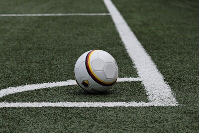 Ein Fu&szlig;ball liegt auf einem Kunstrasenplatz nahe einer wei&szlig;en Ecklinie.