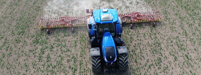 - © Volker Graß Ein blauer Traktor fährt über eine Ackerfläche und bearbeitet das Feld.