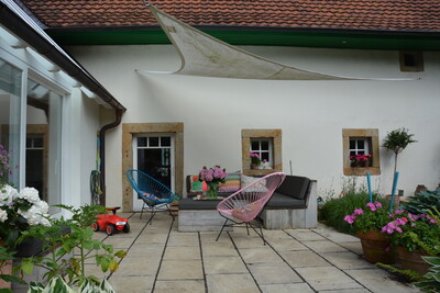 Die Terrasse der jungen Familie liegt geschützt zwischen neuem Anbau, Wohnhaus und einer Eibenhecke. Ein mobiles Leinensegel hält im Sommer etwas Sonnenlicht fern. - © Christiane Rehkamp Terrasse von junger Familie